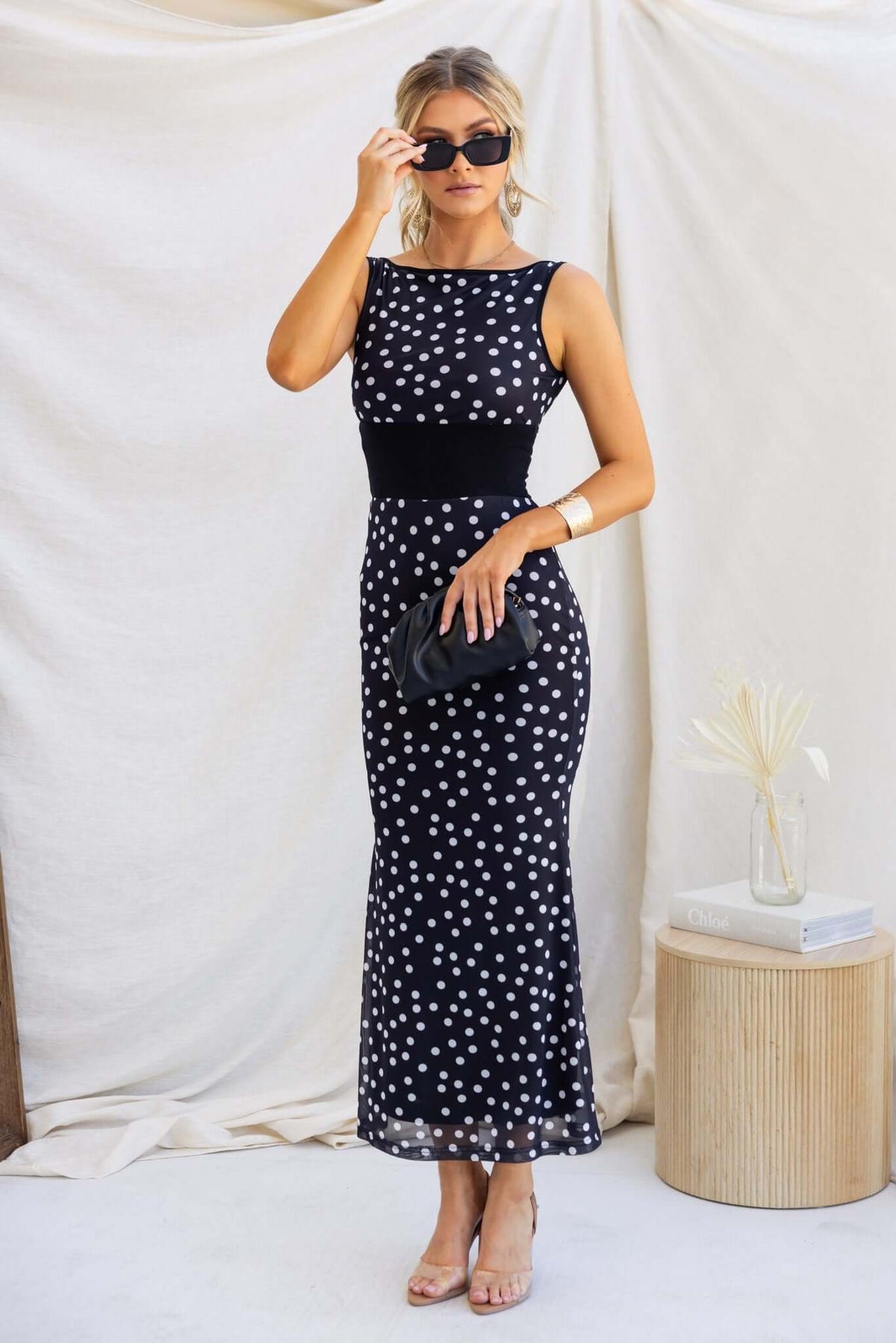 Model wearing a black and white polka dot Loreto Maxi Dress with sunglasses, posing elegantly.