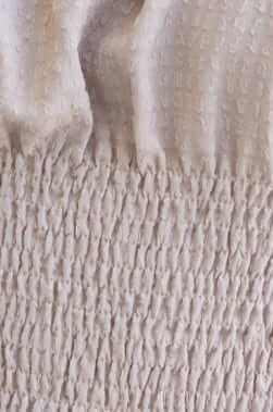 Close-up of Carpi Top fabric showcasing textured smocked bodice and soft beige color.