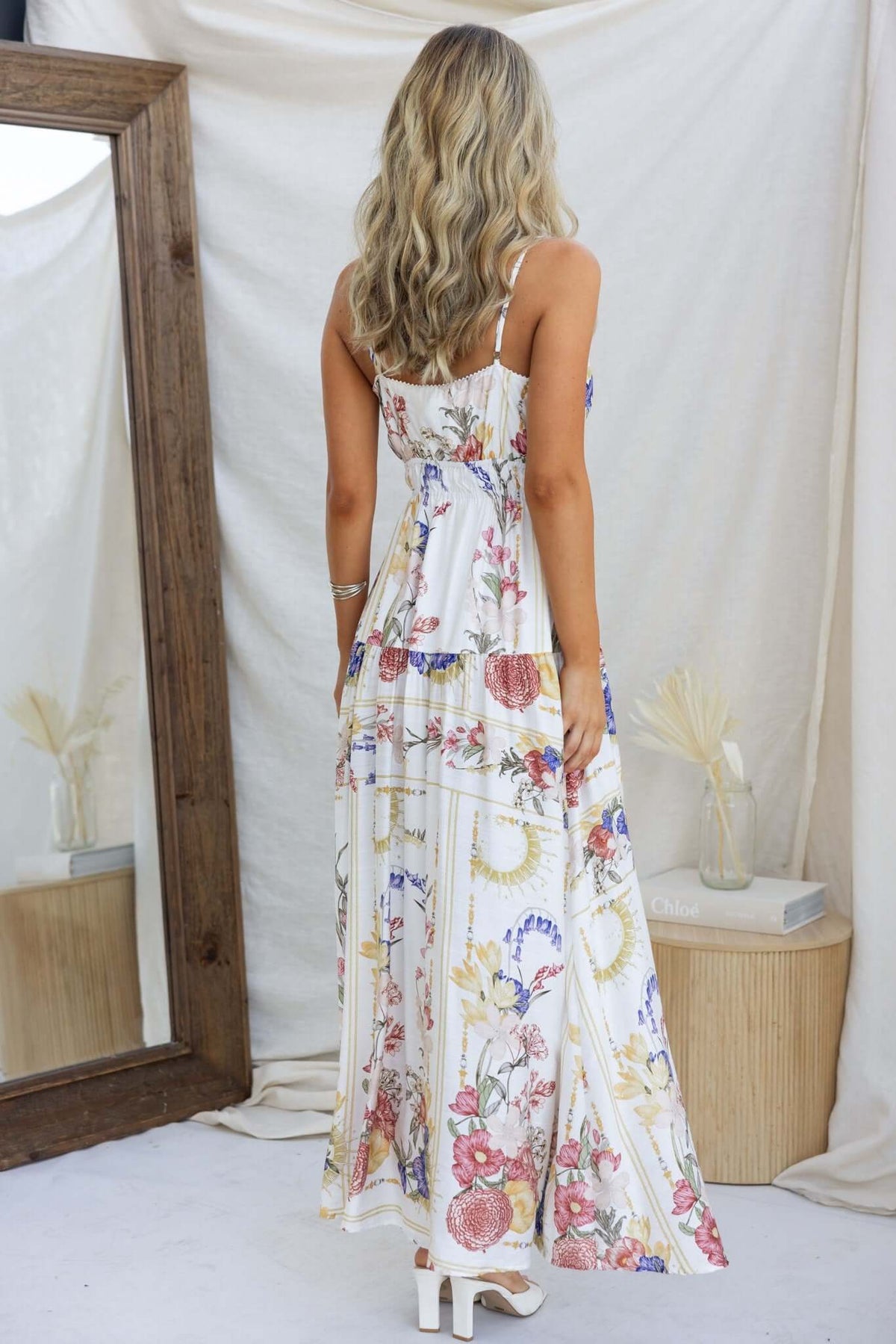 Back view of the Garlyn Maxi Dress, featuring adjustable straps and floral print, styled elegantly with a mirror.