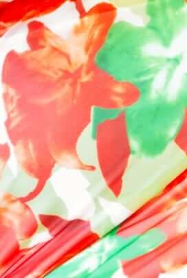 Close-up of vibrant floral fabric in red and green, showcasing the mesh material of the Inaya Maxi Dress.