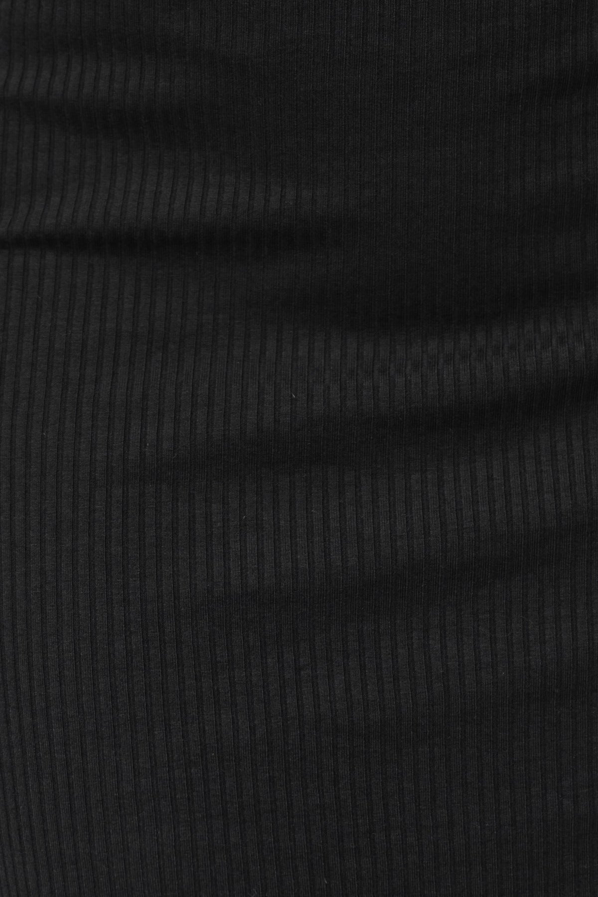 Close-up of black ribbed fabric, showcasing the stretch and texture ideal for a stylish and comfortable dress.