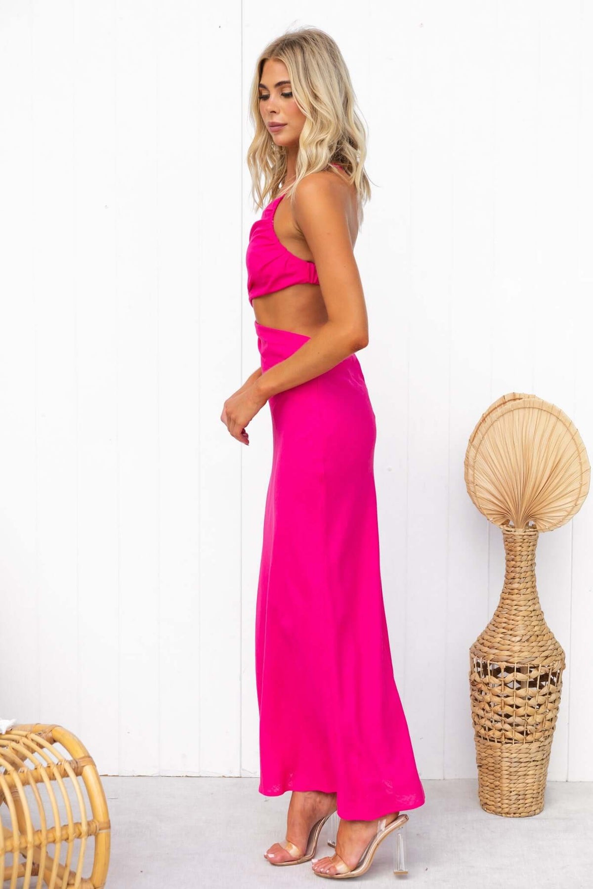 Model in a pink Aradia midi dress featuring an asymmetrical neckline and adjustable straps.