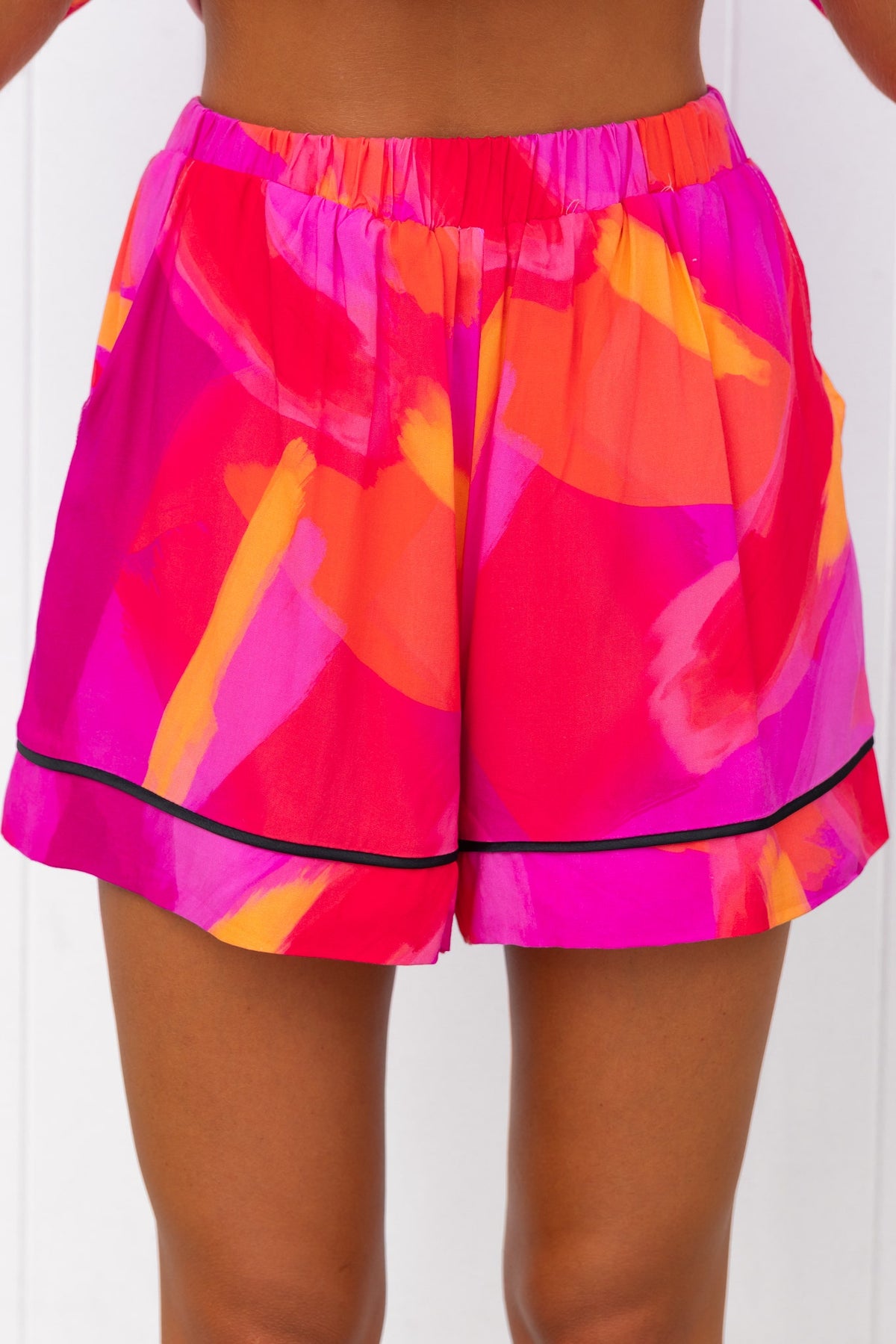 Bright pink print shorts with mid-high waist, elastic waistband, and pockets, ideal for summer outfits.
