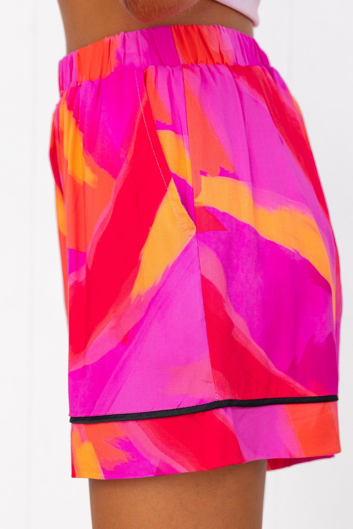 Colorful mid-high waist Focus Shorts with elastic waistband and pockets, featuring a vibrant pink and orange print.