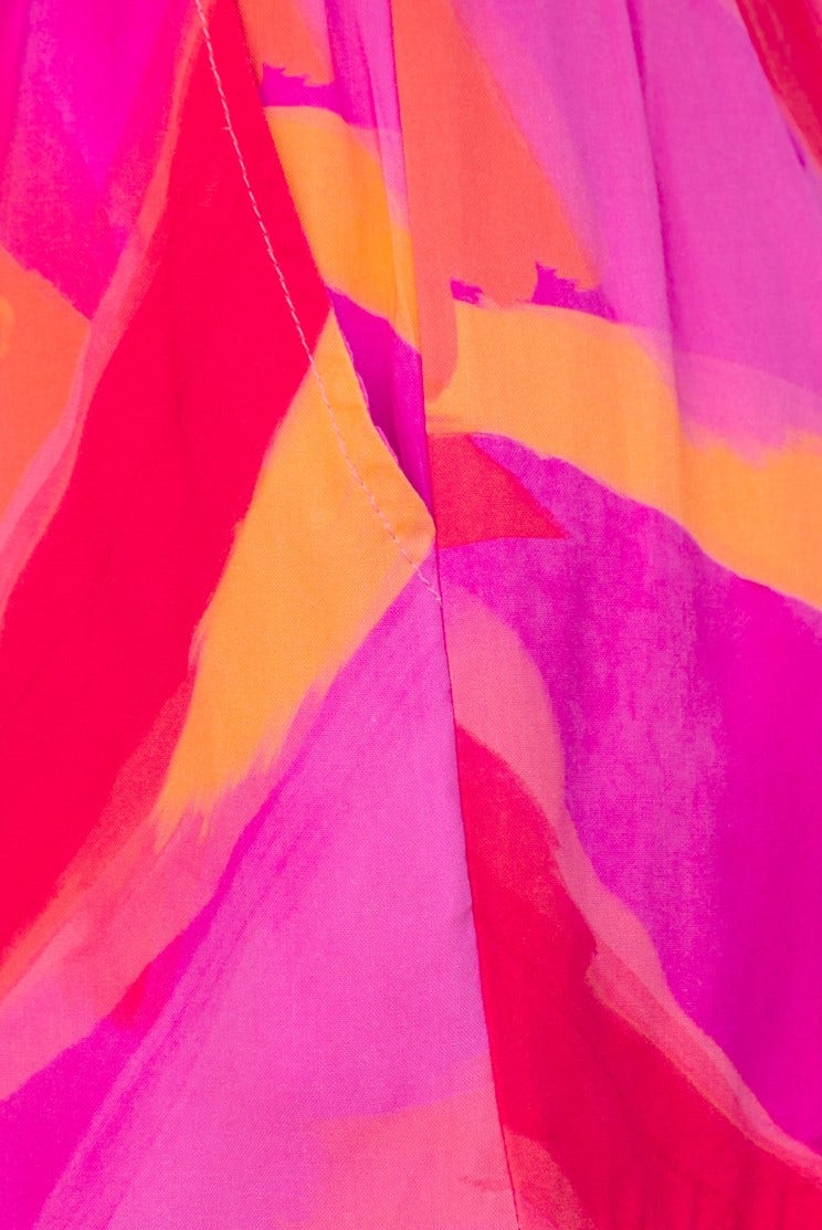 Close-up of vibrant pink and orange abstract pattern on lightweight fabric, ideal for summer fashion.