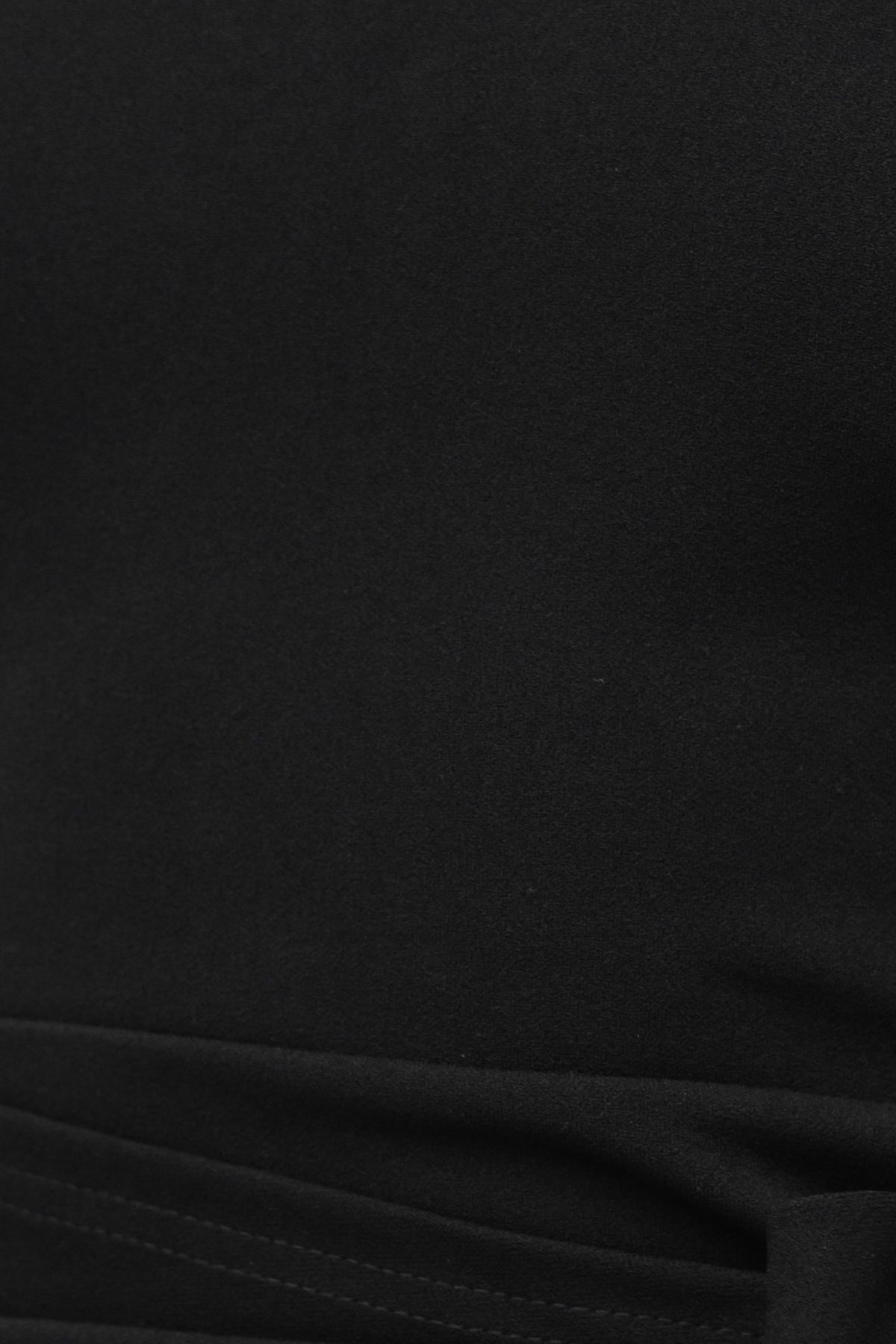Close-up of the Hayman Dress in black crepe material, showcasing the one-shoulder neckline and wrap-look tie detail.