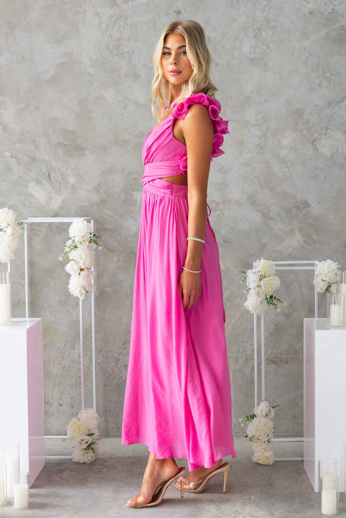 Side view of a model in a pink Luciana Maxi Dress with ruffle straps and stylish cut-out detail at the waist.