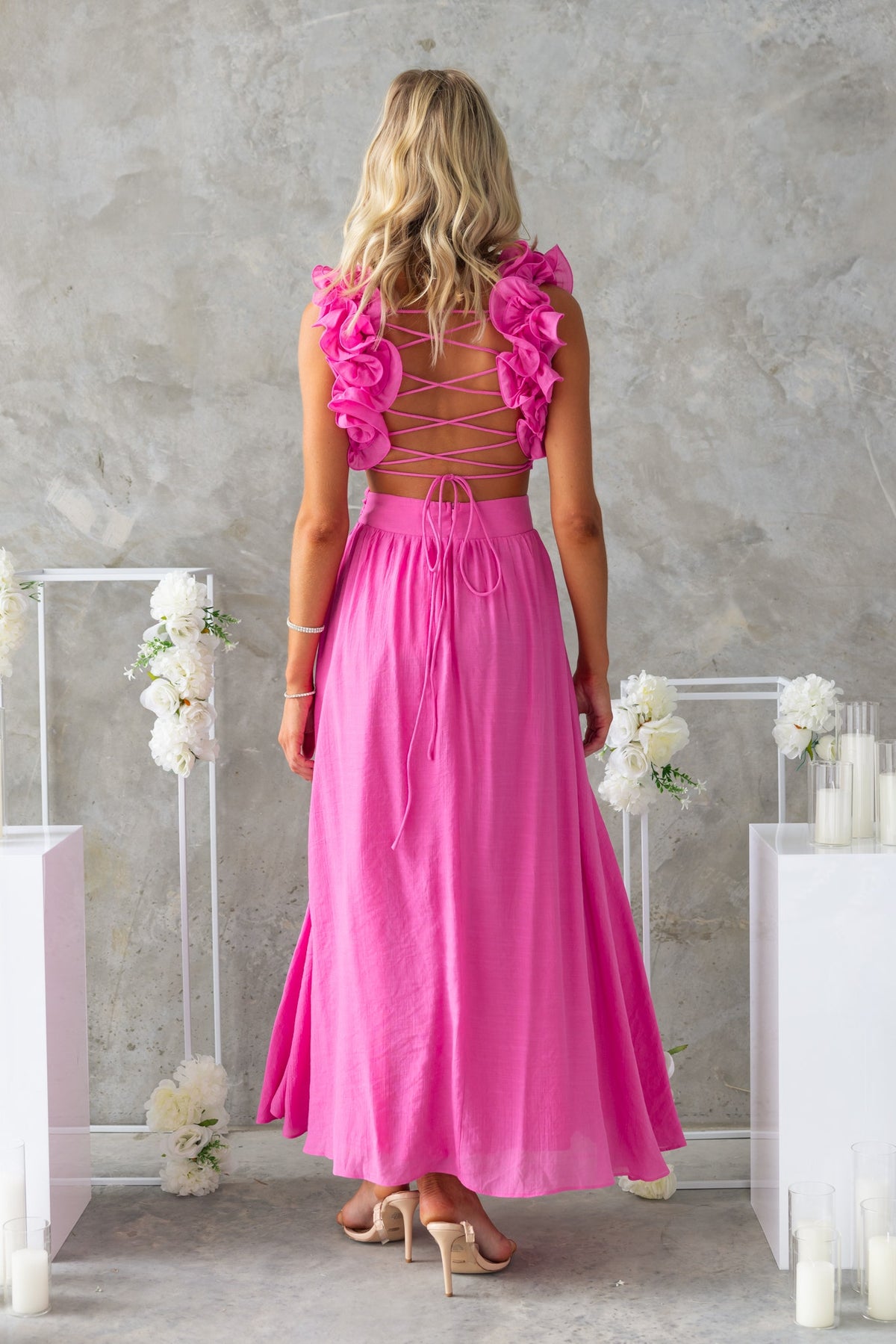 Back view of Luciana Maxi Dress in pink with ruffle straps and lace-up detail, perfect for summer occasions.