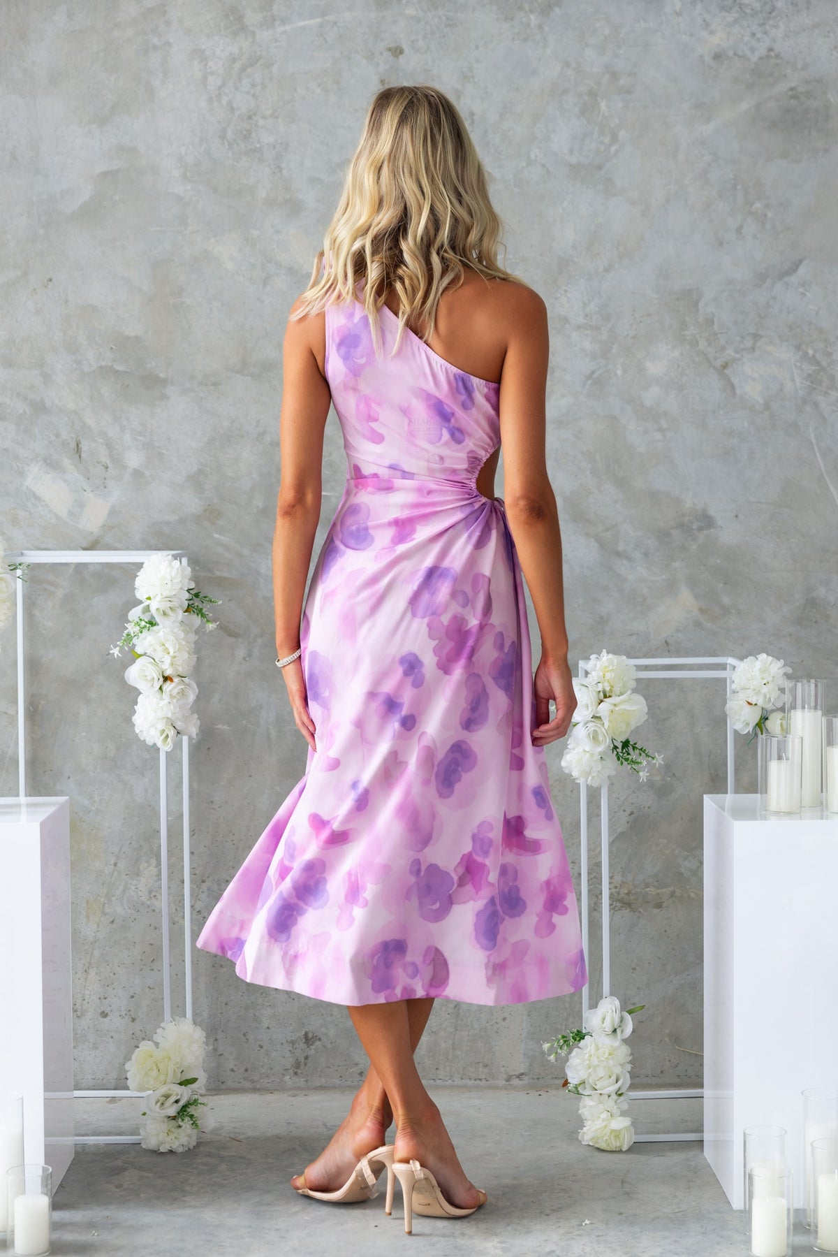 Back view of Ikaris Midi Dress in floral print, featuring one-shoulder design and cut-out waist with ruching.