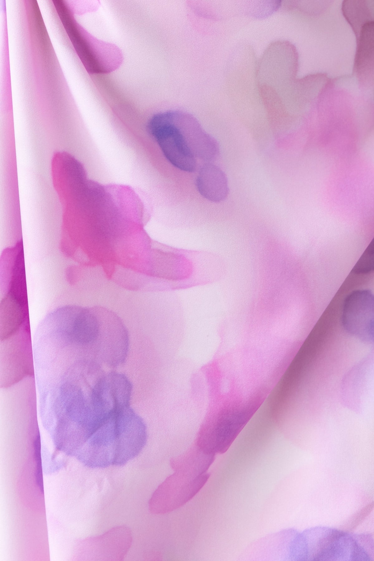Close-up of soft pink and purple floral print fabric suitable for a dress, showcasing delicate watercolor effects.