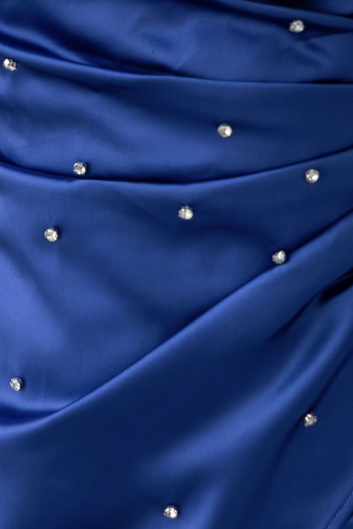 Close-up of blue dress fabric with pleats and sparkling diamante embellishments.