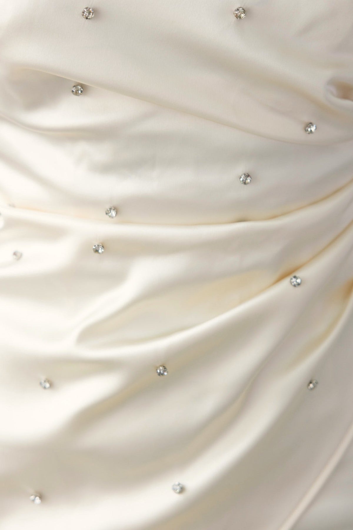 Close-up of Love More Dress featuring elegant fabric with gem embellishments and soft draping.