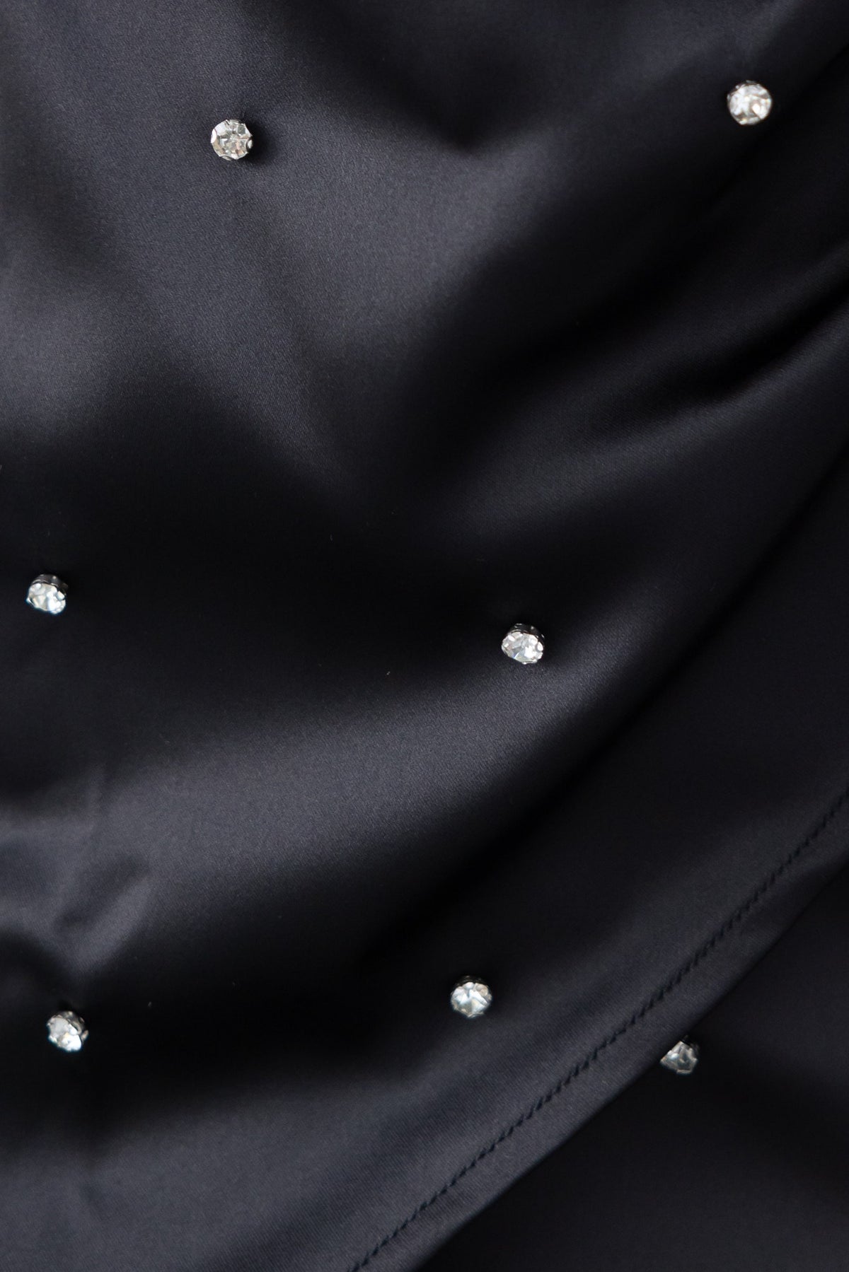 Close-up of a black fabric featuring sparkling diamante embellishments elegantly scattered across the surface.