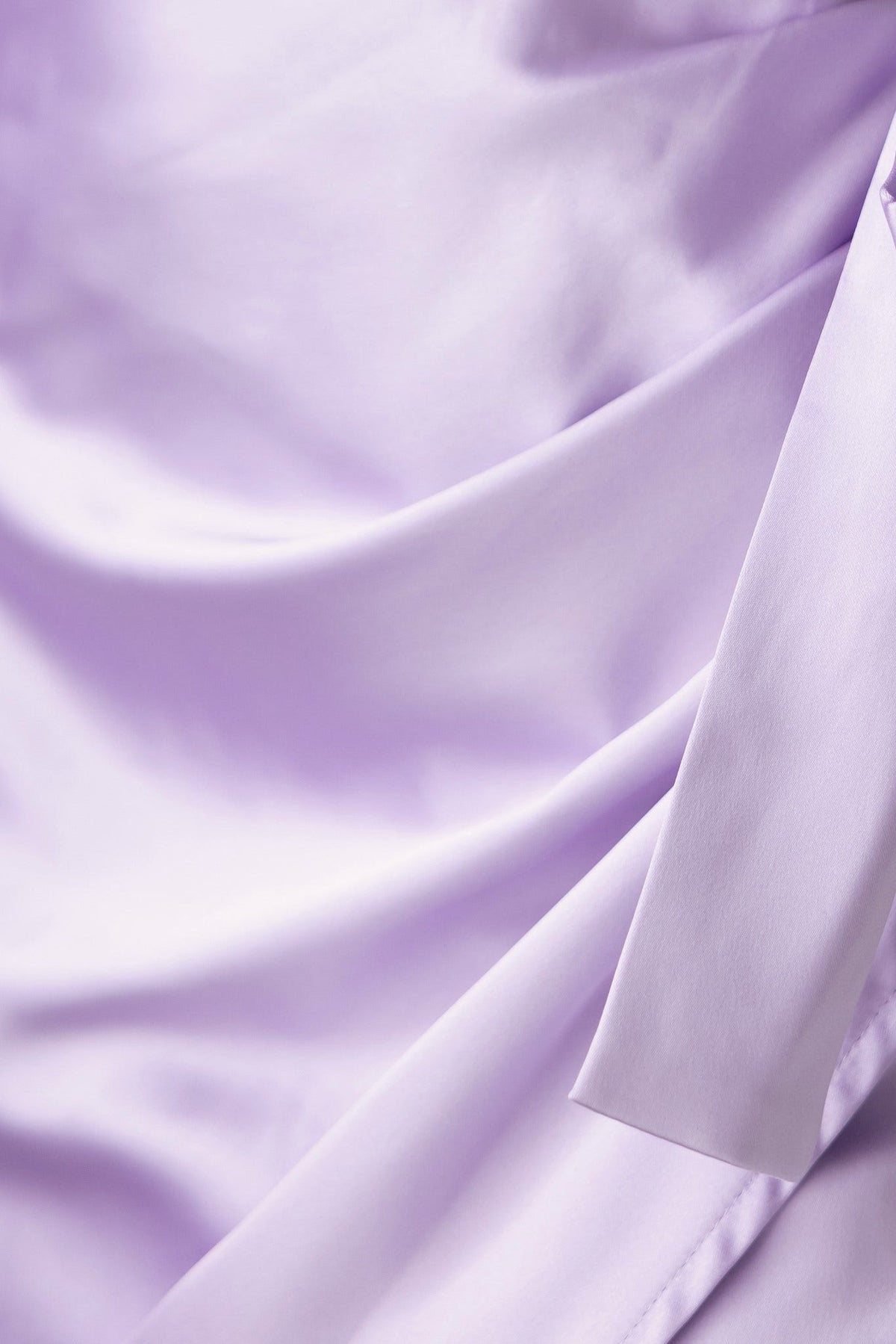 Close-up of soft lavender satin fabric, showcasing the elegant drape and sheen of the material.