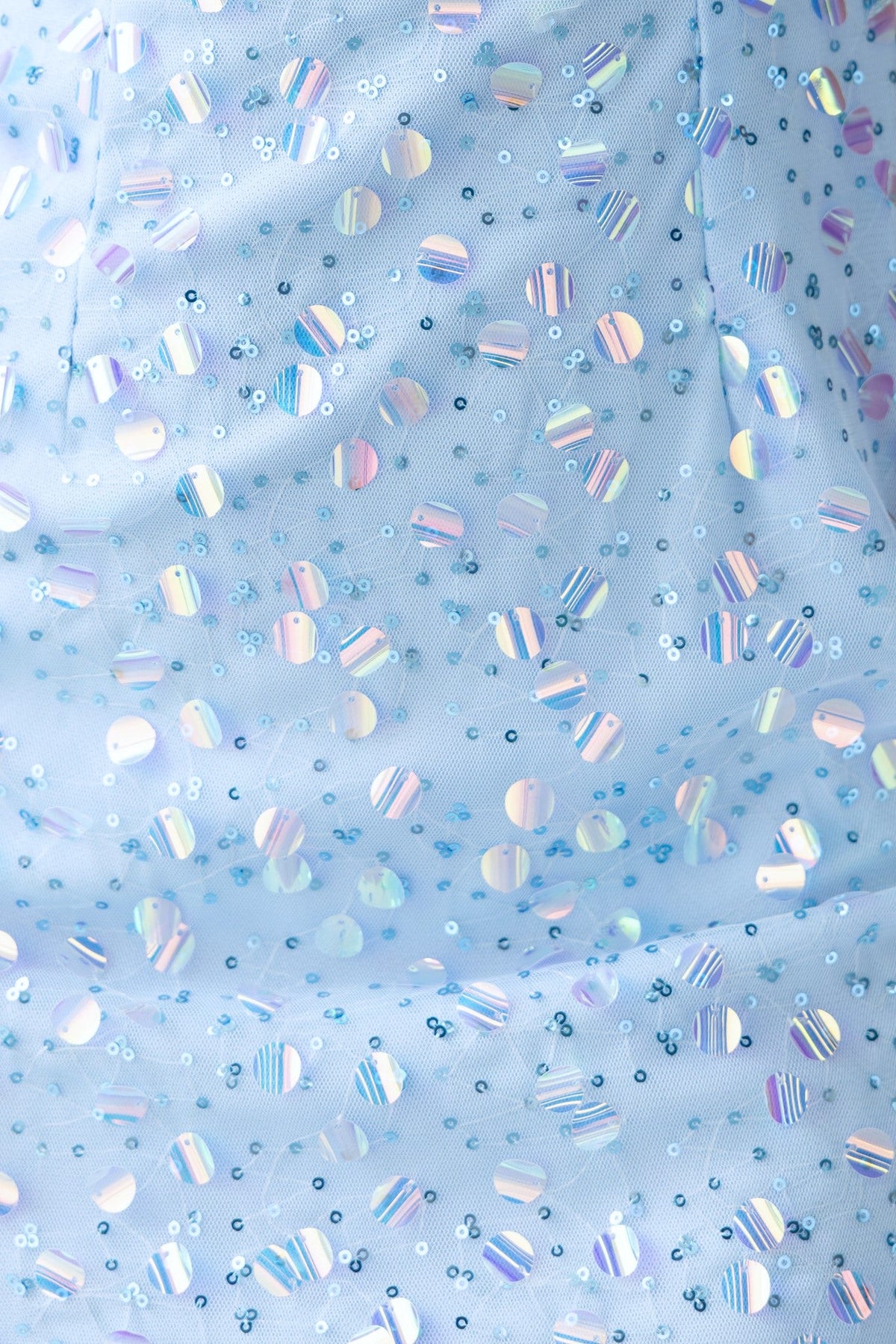 Close-up of sequined mesh fabric in light blue, featuring round and striped reflective sequins.