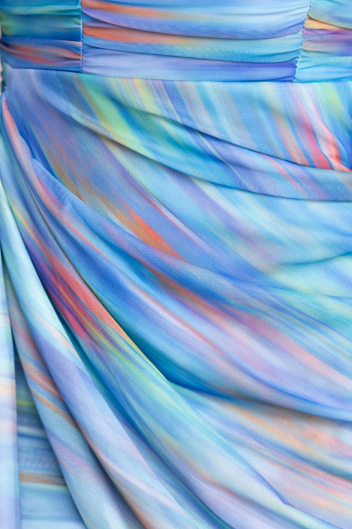 Close-up of the draped fabric of the Make Me Blush Dress featuring colorful mesh overlay and soft pastel hues.