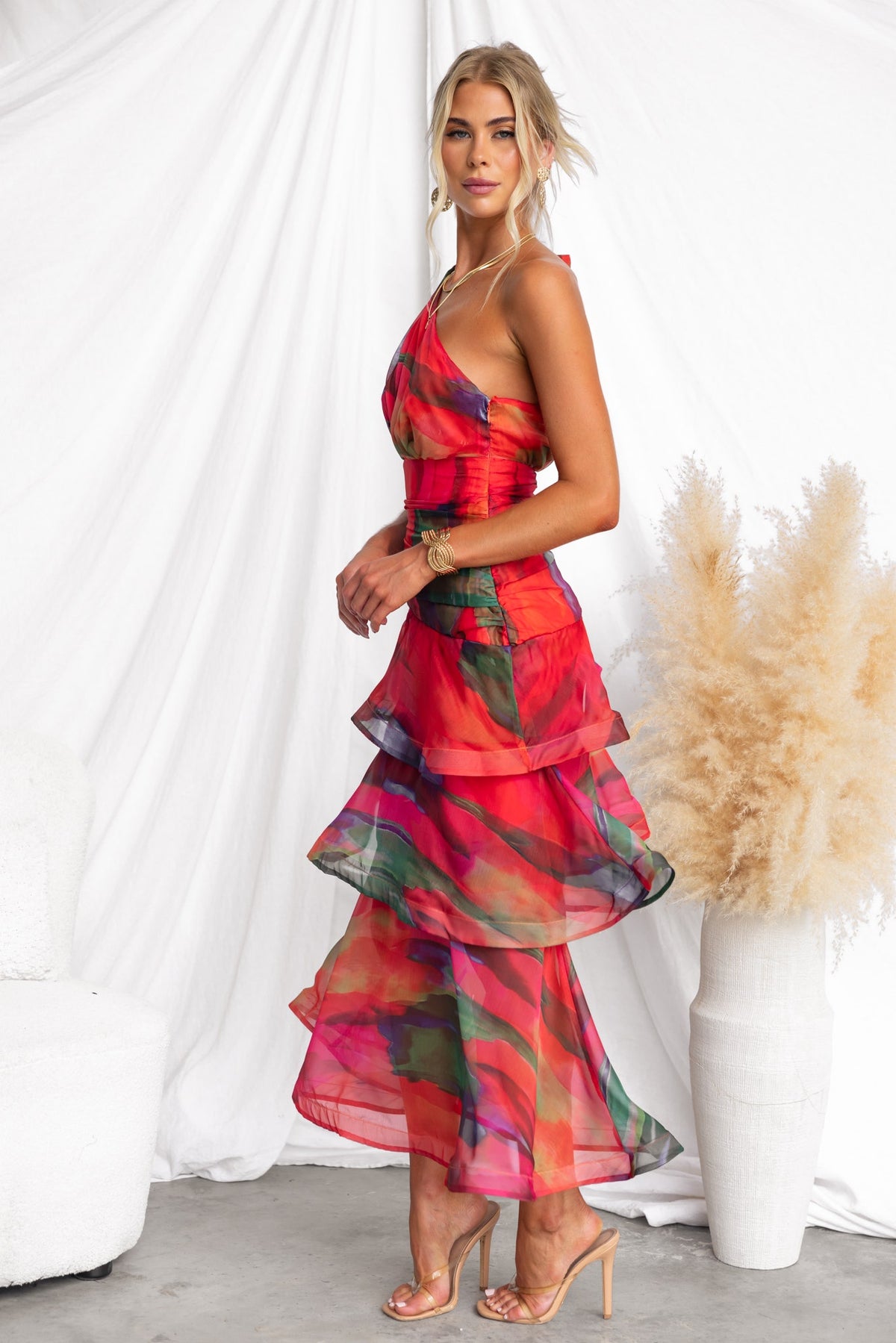 Model wearing a vibrant Sherbert Midi Dress with one-shoulder neckline and layered ruffle hem.