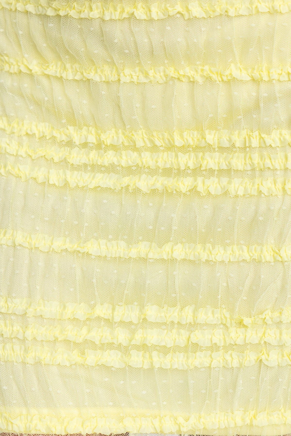 Close-up of a textured yellow fabric with ruffled layers and polka dots, ideal for a stylish maxi skirt.