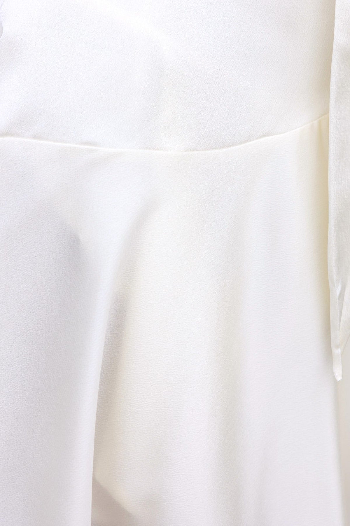 Close-up of the Xention dress showcasing its soft, white satin fabric and elegant flowing silhouette.