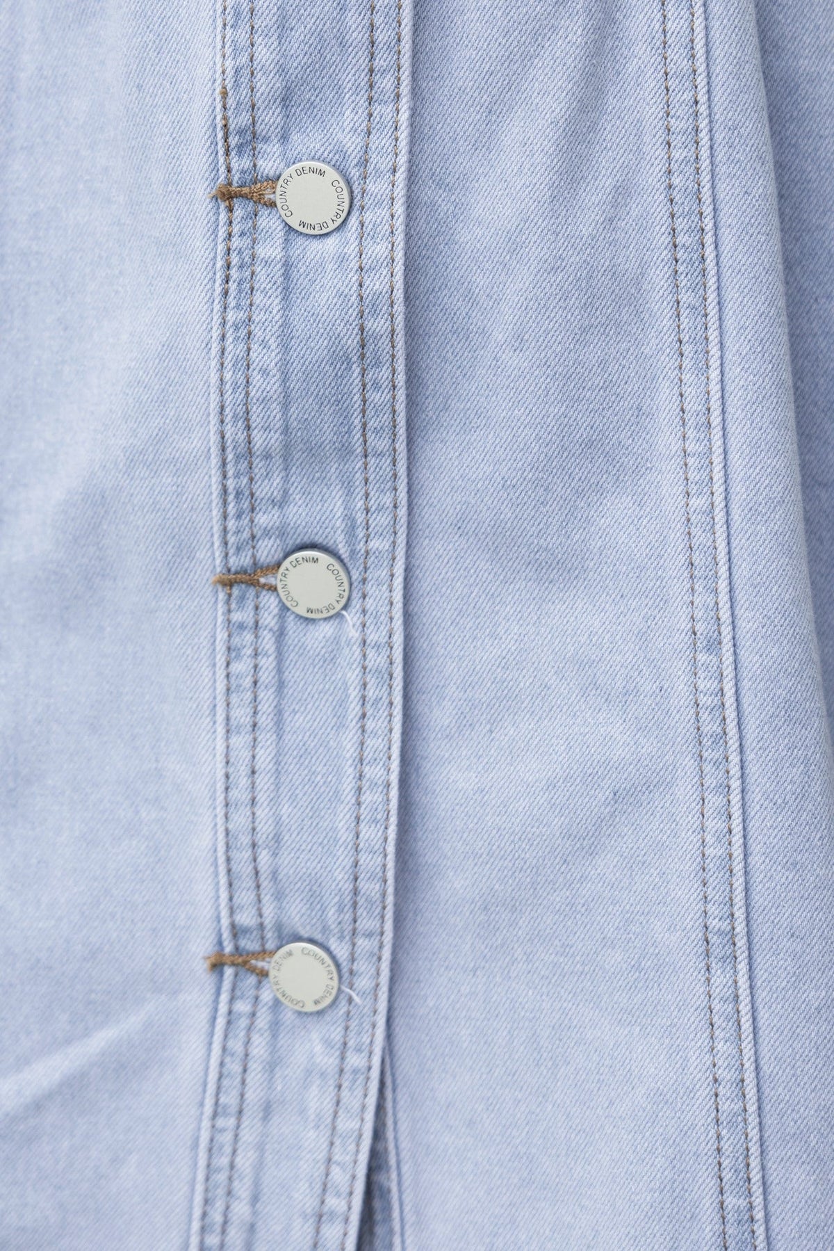 Close-up of Carlia Denim Dress showing button-up front and soft, light blue denim fabric.