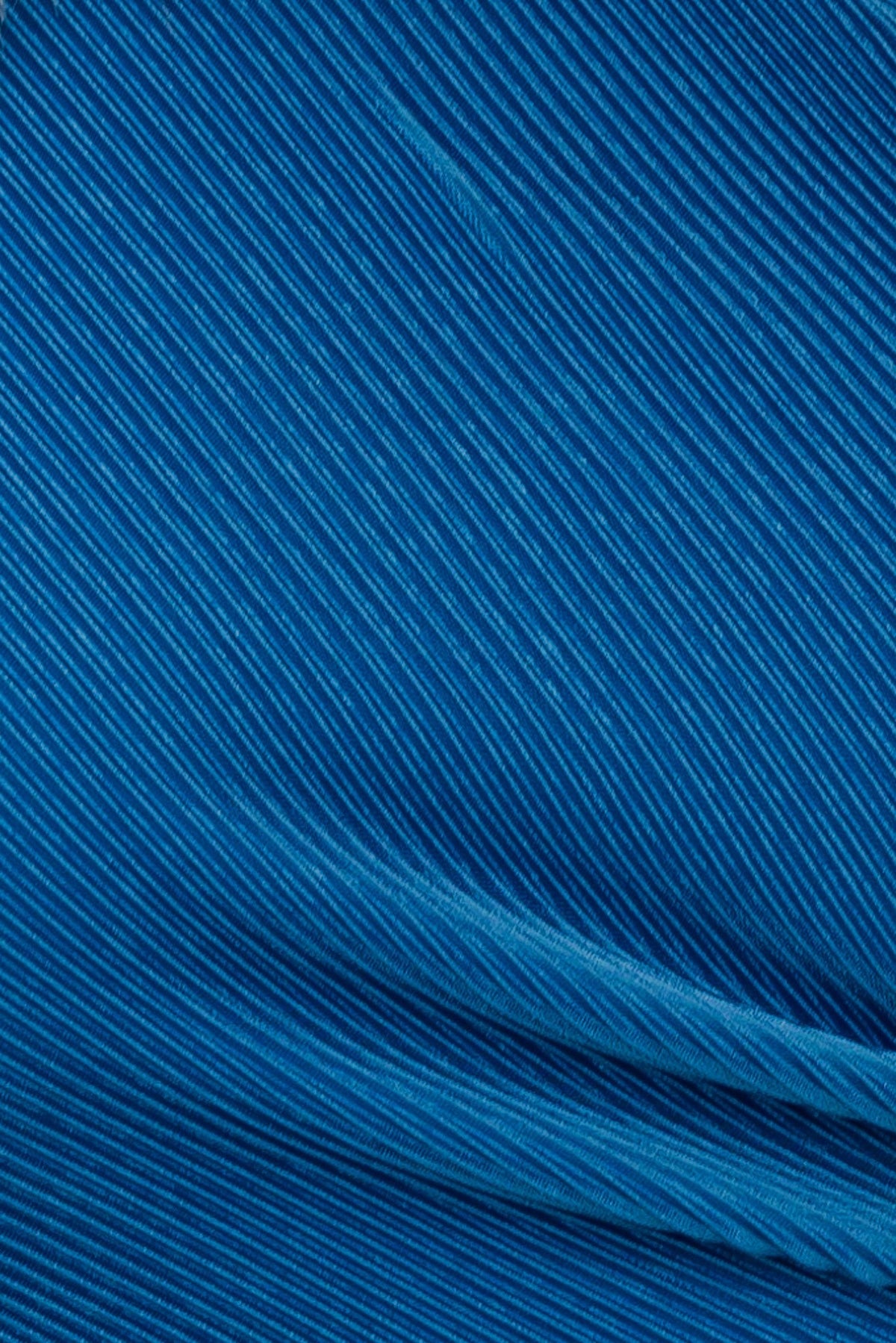 Close-up view of accordion pleat material in vibrant blue fabric, showcasing texture and stretch for stylish pants.