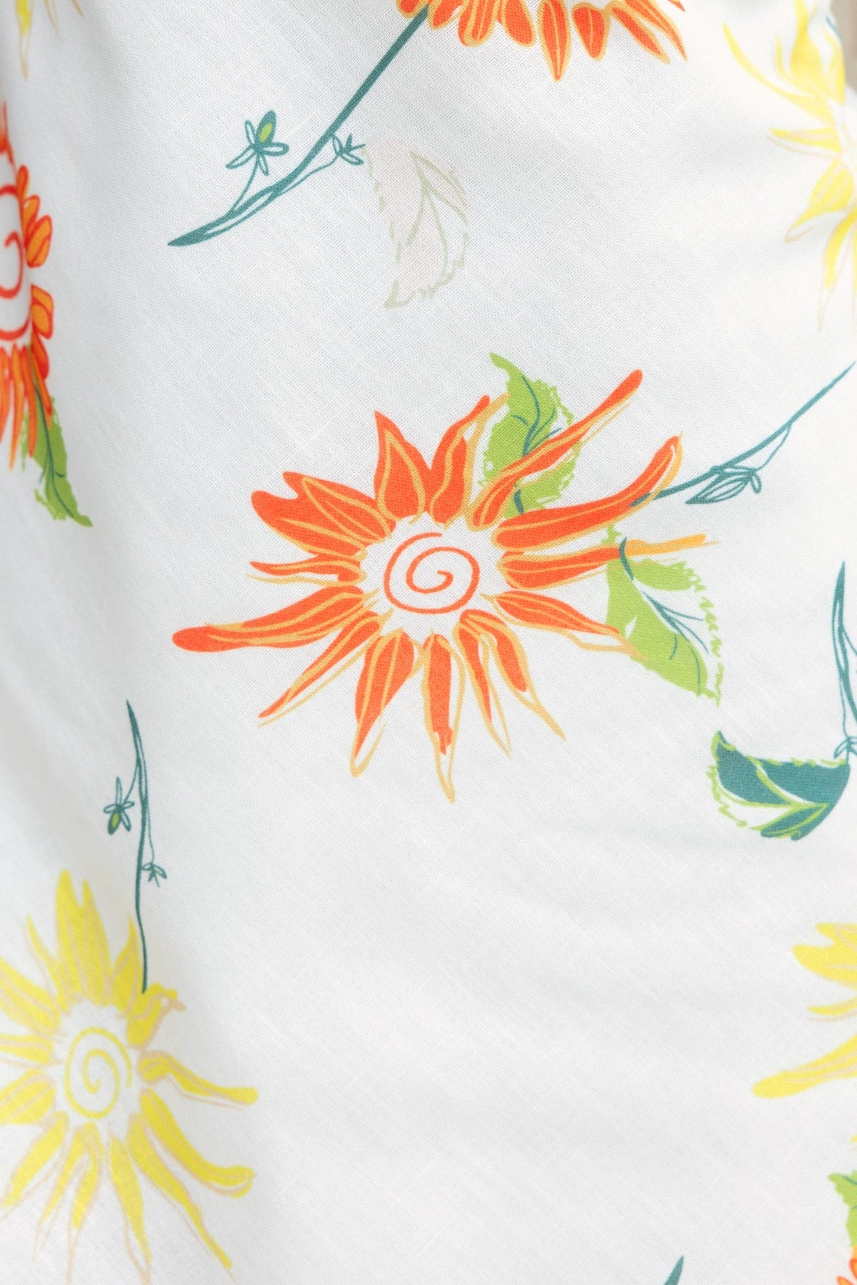 Close-up of vibrant floral print featuring orange and yellow flowers on a soft white fabric.