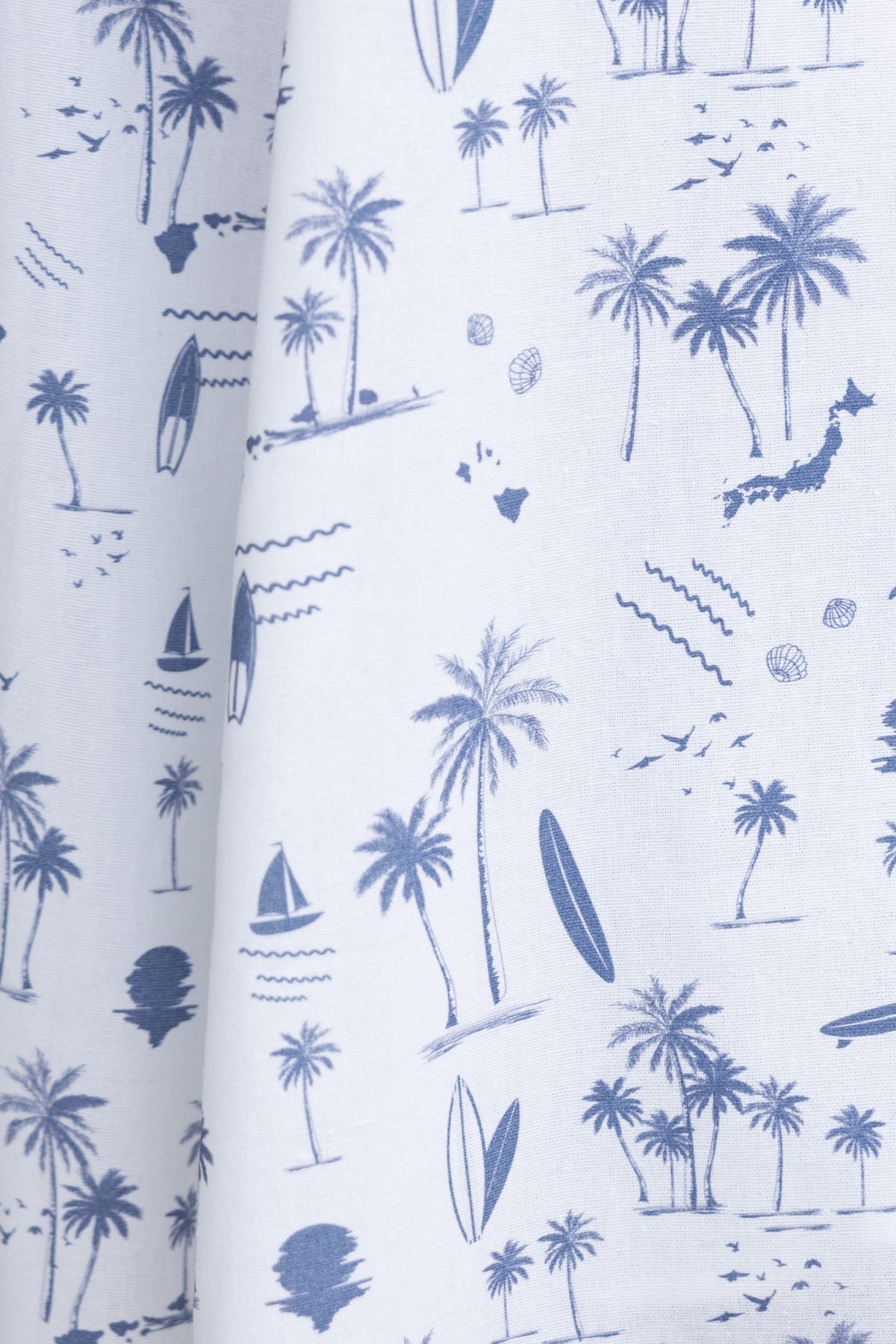 Blue and white fabric featuring a tropical print with palm trees, boats, and waves, perfect for summer apparel.