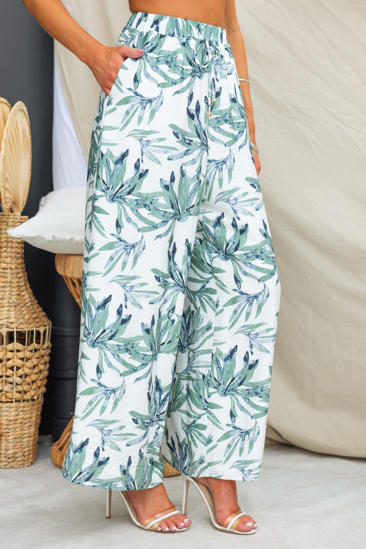 Lavina floral print pants with elastic waistband, mid-high waist, and pockets, styled with heels.