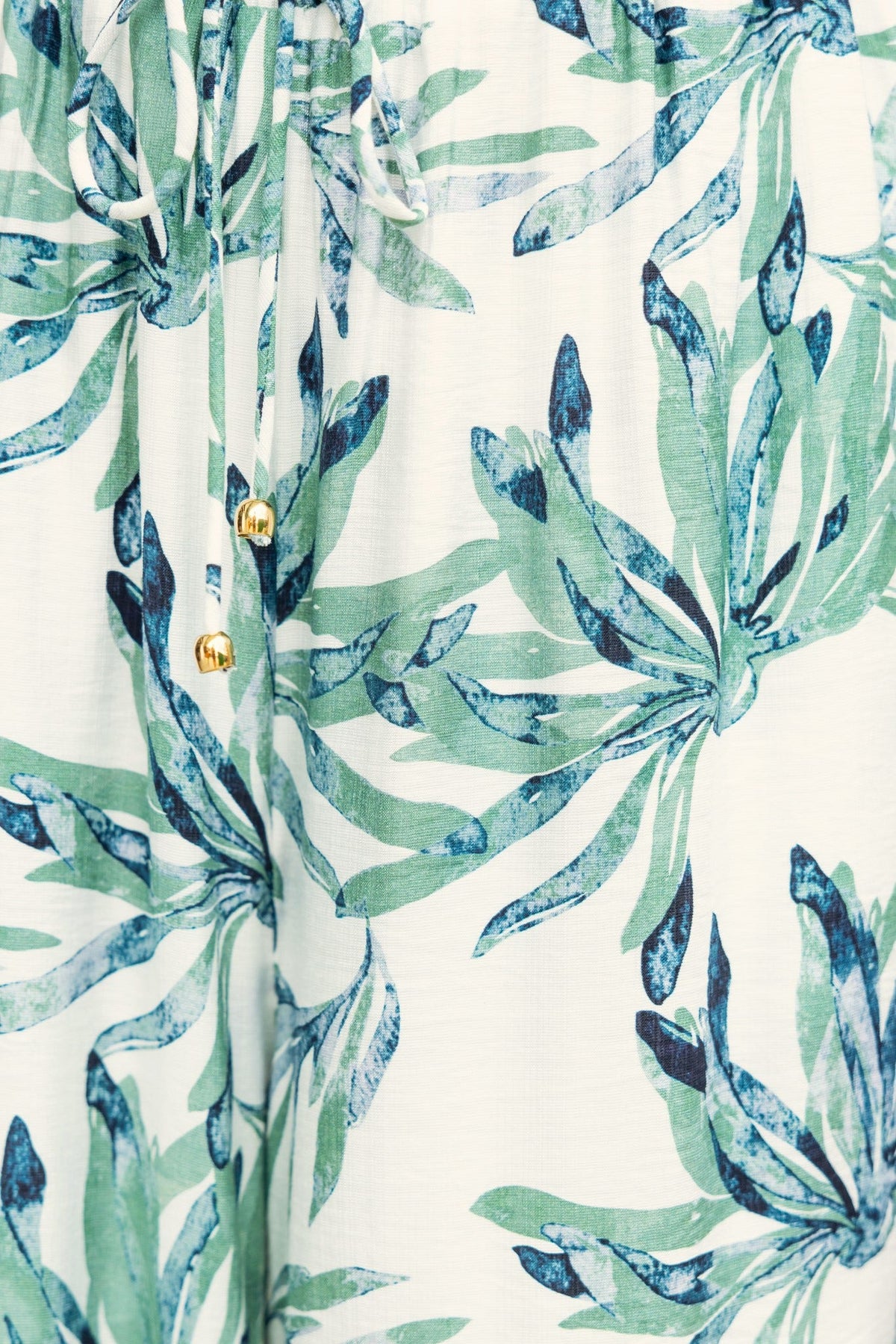 Floral print detail of Lavina Pants featuring green leaf patterns and elastic waistband for comfortable fit.