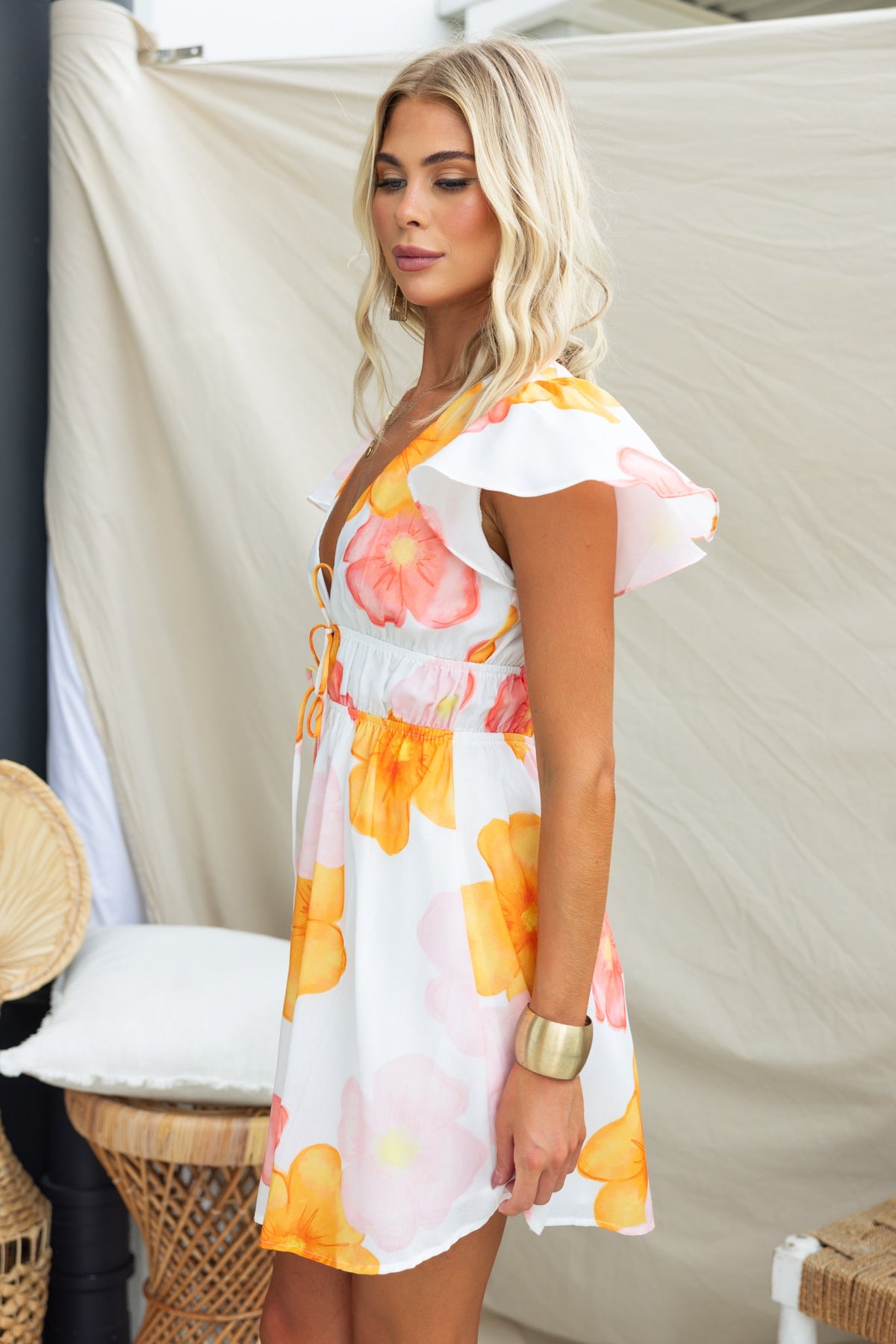 Milene dress featuring floral print, V-neckline, tie detail, and elastic waistband, styled for a summer look.