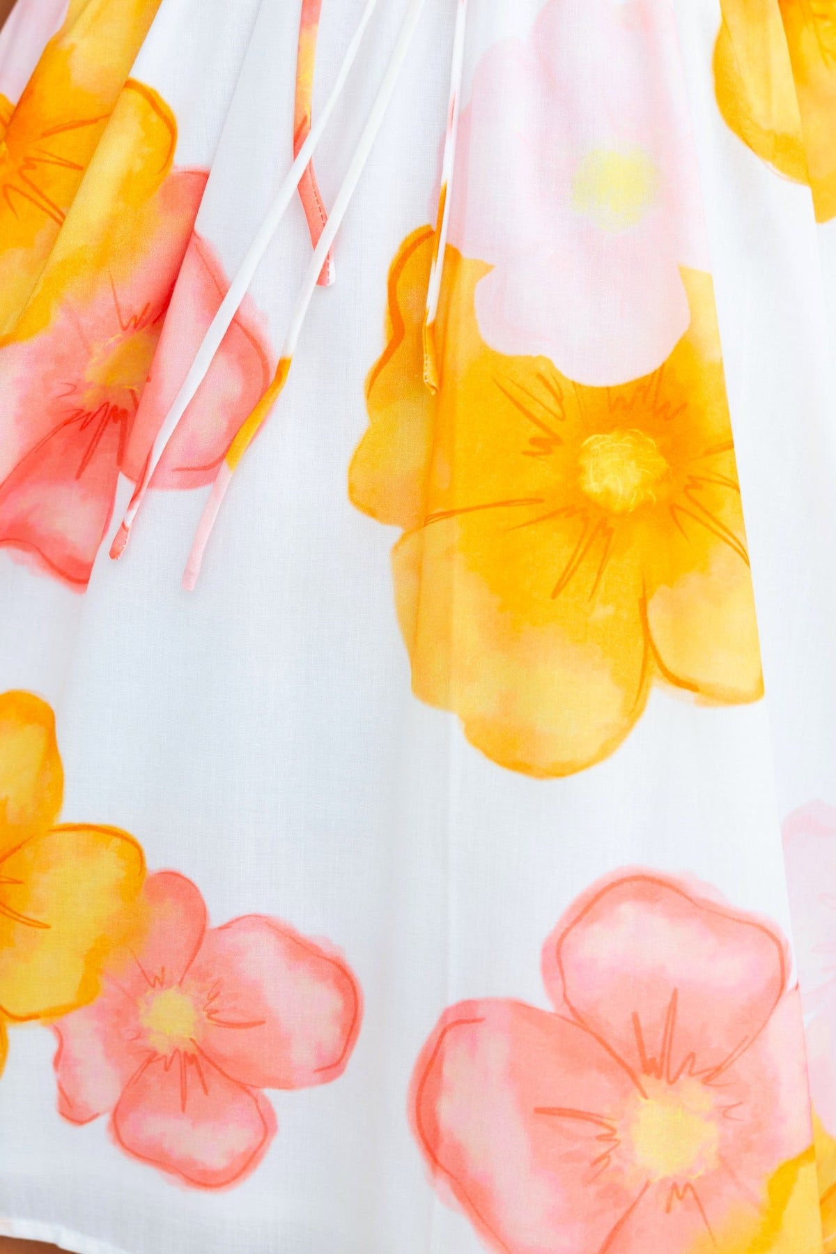 Close-up of floral print featuring orange and pink flowers on a white background, showcasing the design of the Milene Dress.