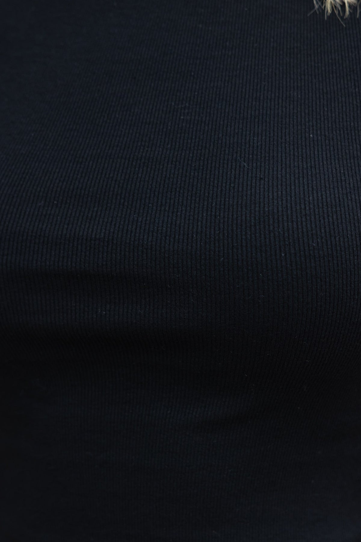 Close-up of black ribbed cotton material in a stretchy t-shirt, showcasing the texture and fit.