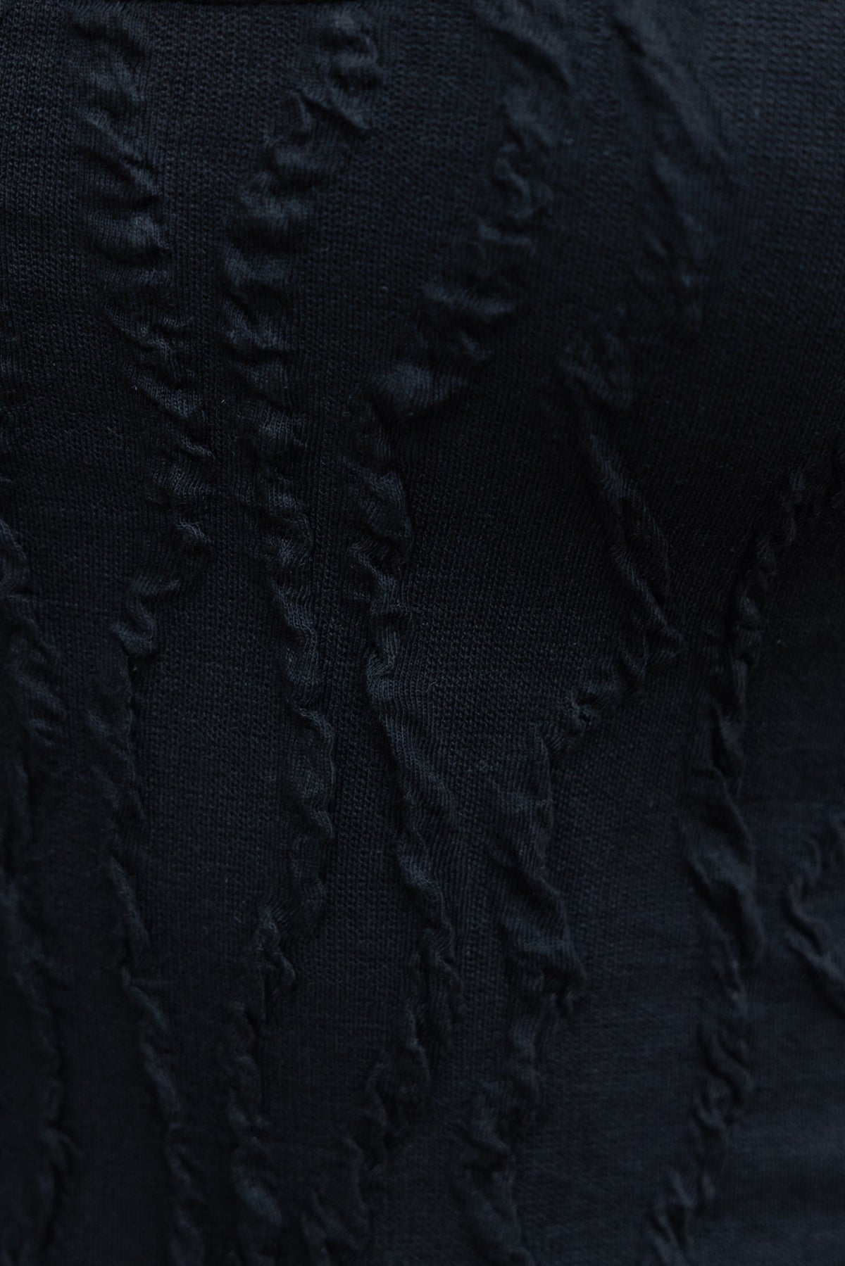 Close-up of textured black fabric showcasing intricate design, perfect for stylish bodysuits.