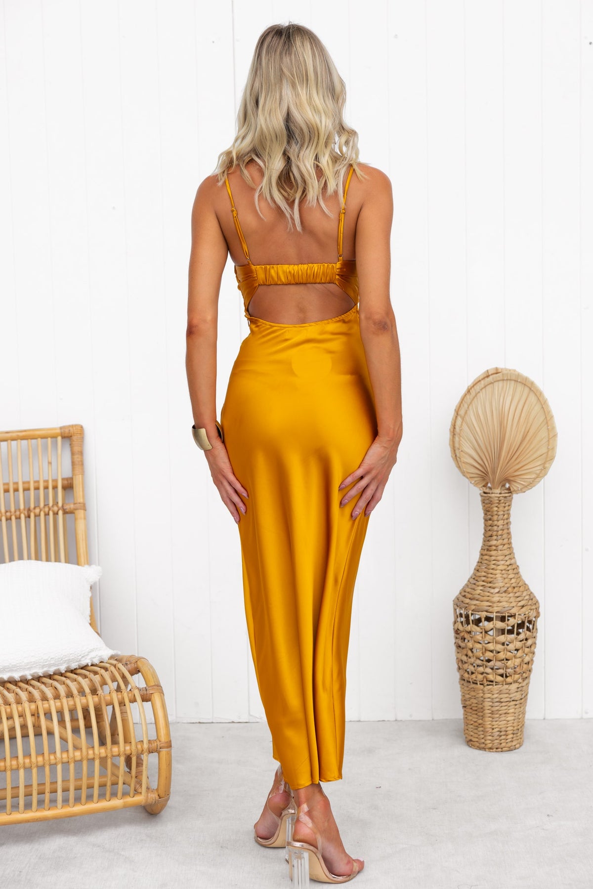 Back view of Alyna Maxi Dress with adjustable straps and twist detail, showcased in a chic setting.