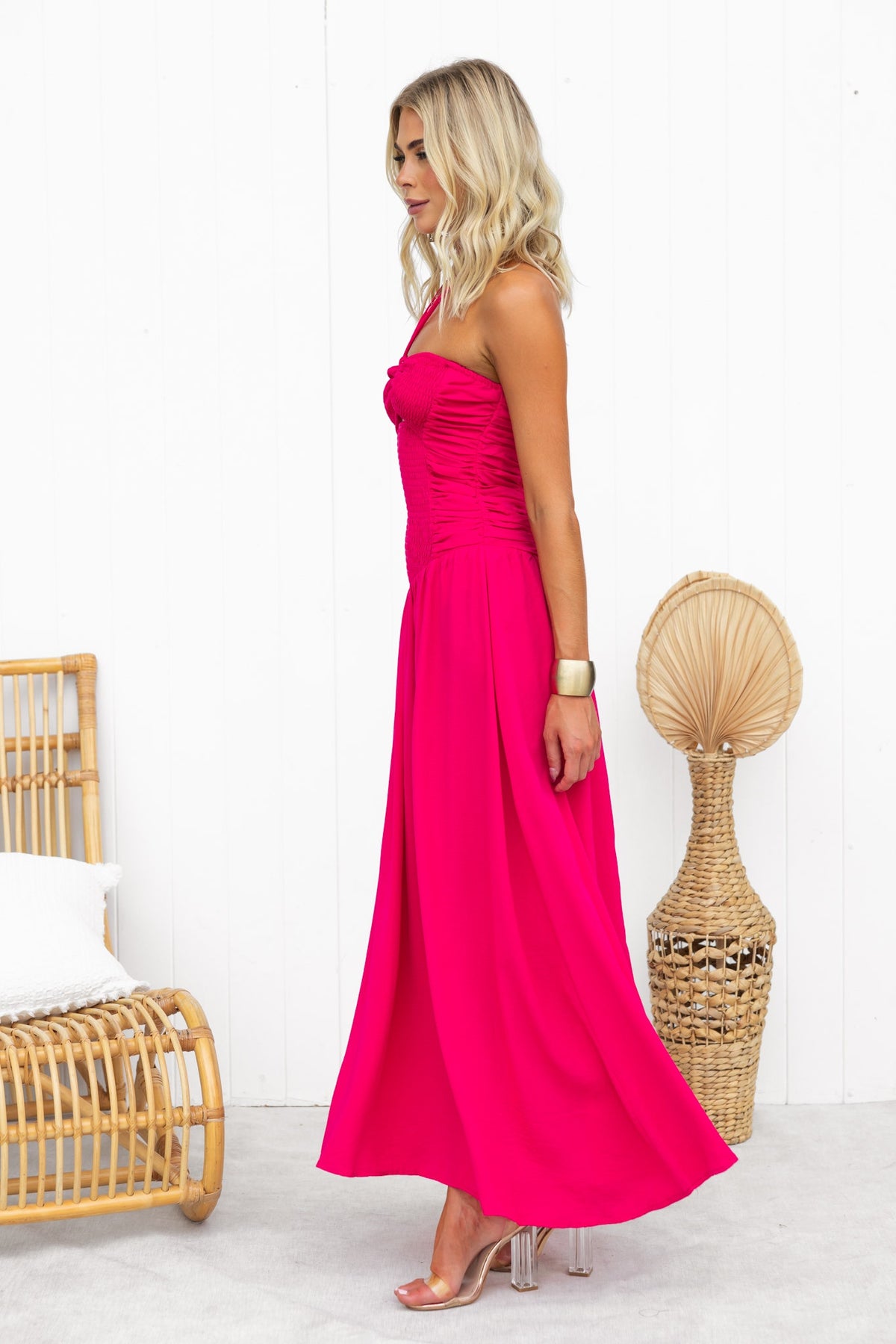 Model wearing a vibrant pink Jayma Maxi Dress featuring a tie neckline and elegant flow, styled with a chic bracelet.