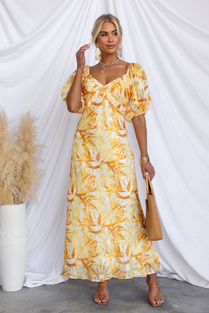 Stylish floral print Samaya maxi dress with V-neckline and elastic sleeves in vibrant yellow shades.