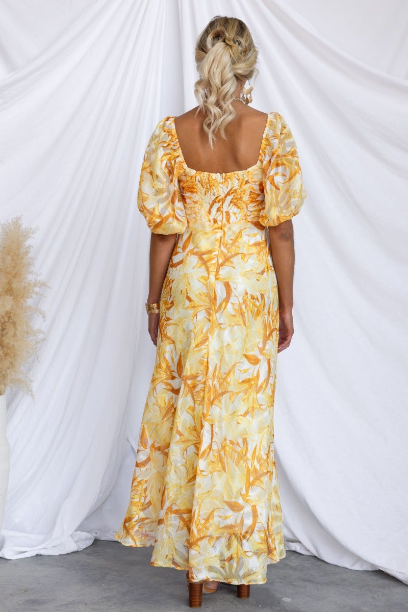 Back view of the Samaya Maxi Dress featuring a floral print, V-neckline, and puff sleeves against a white backdrop.
