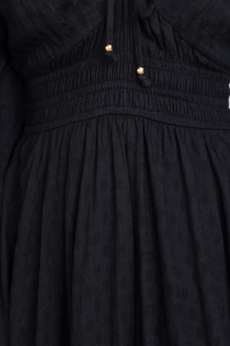 Close-up of the Hemingway Midi Dress showing elastic waist and tie detail on neckline in black cotton fabric.