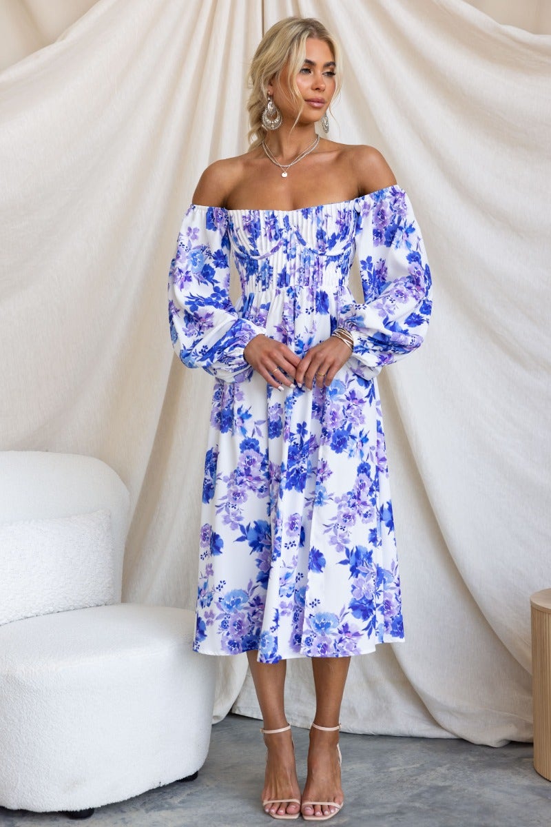 Model wearing a floral print Lost Love Midi Dress with off-the-shoulder style and balloon sleeves in blue and white.