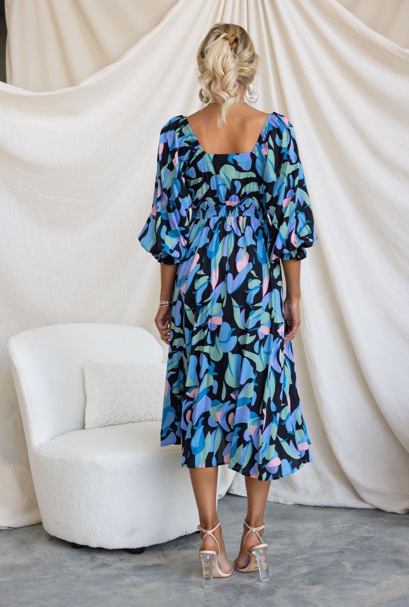 Back view of the Clemence Midi Dress featuring a colorful floral print and elastic sleeve fittings.