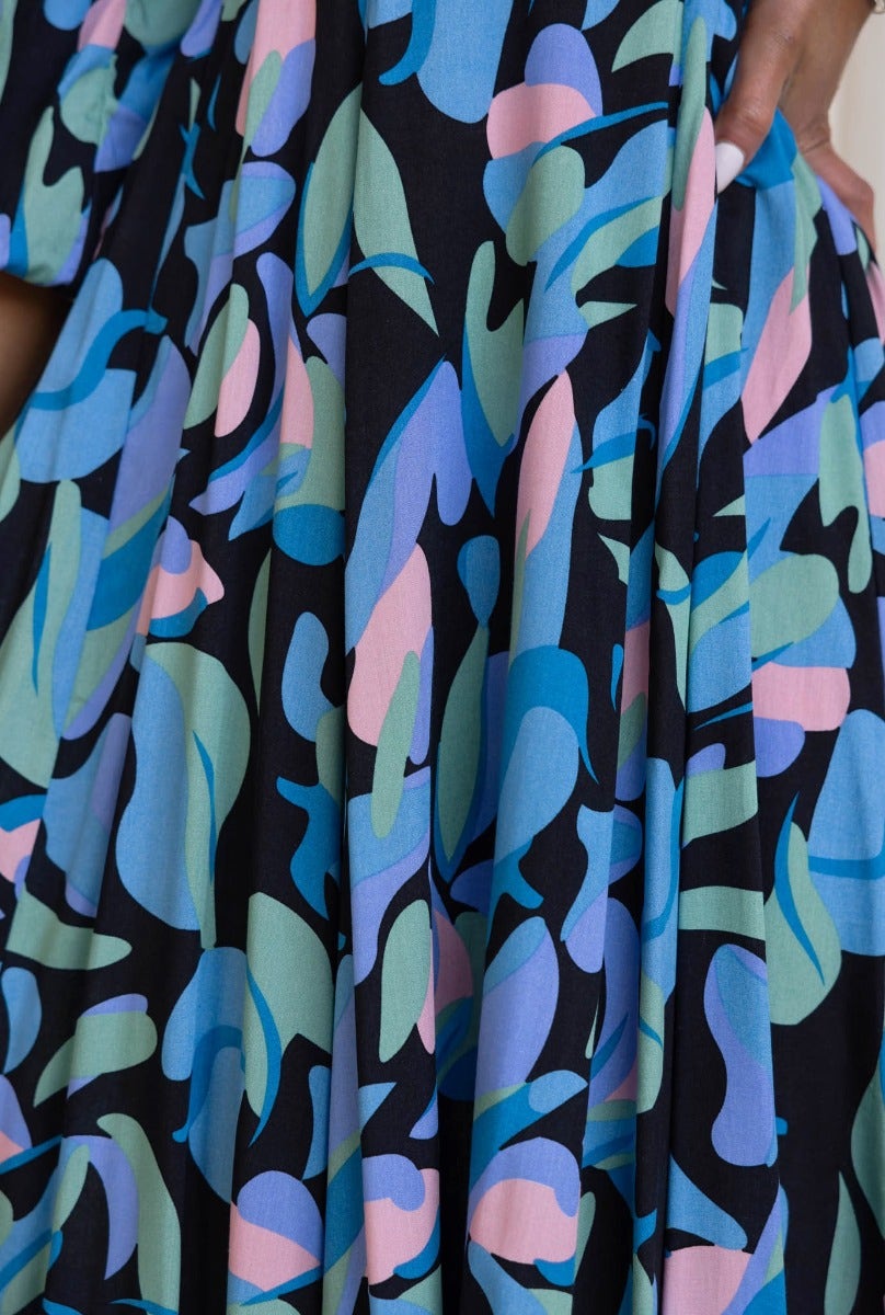 Colorful floral print close-up of the Clemence Midi Dress in black, featuring shades of blue, green, and pink.