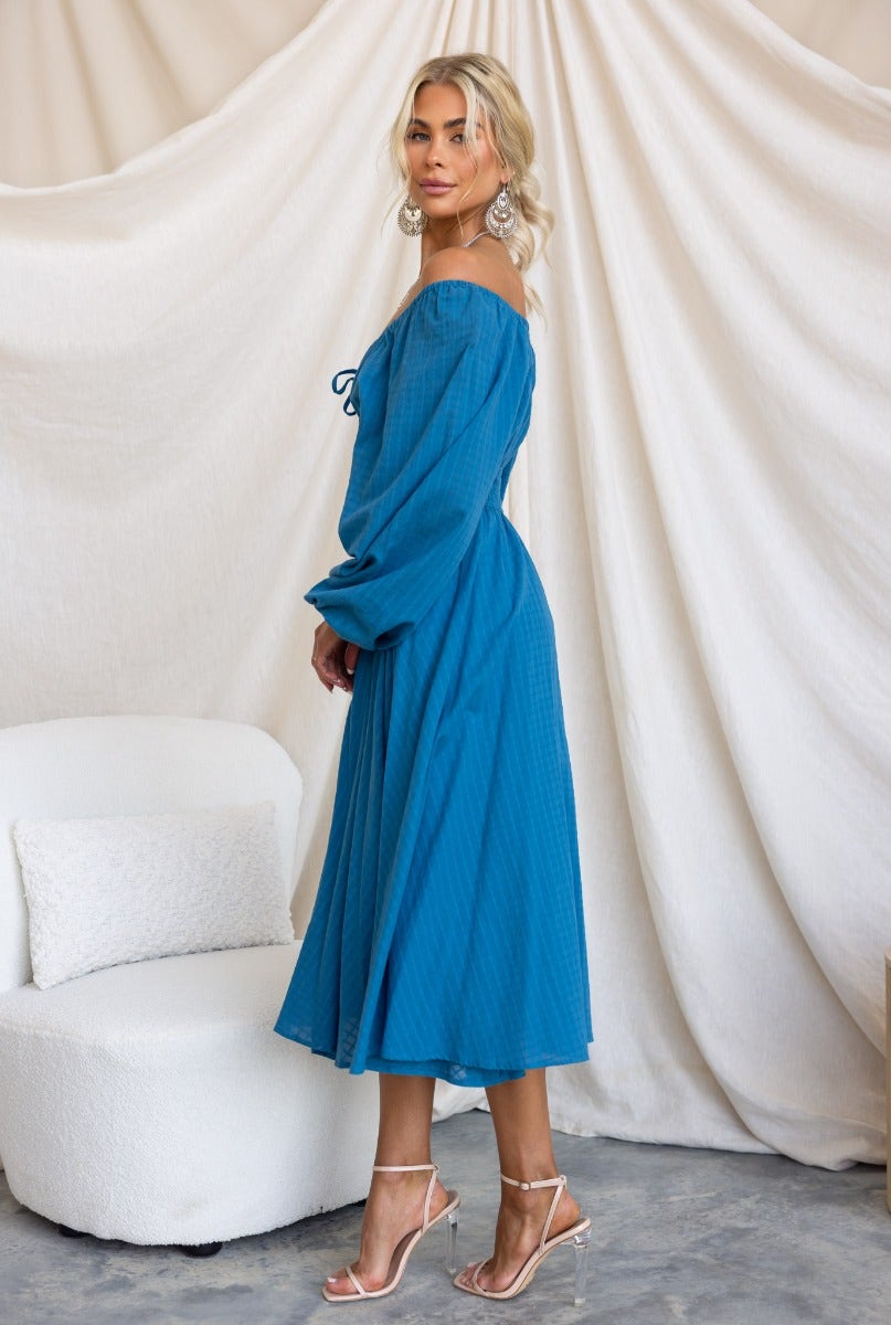Hemingway midi dress in blue, featuring off-shoulder style, long sleeves, and tie detail, perfect for elegant summer outings.