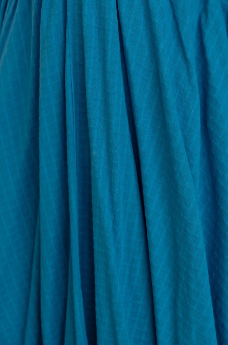 Close-up of textured blue fabric showcasing the intricate pleats and draped design of the Hemingway Midi Dress.