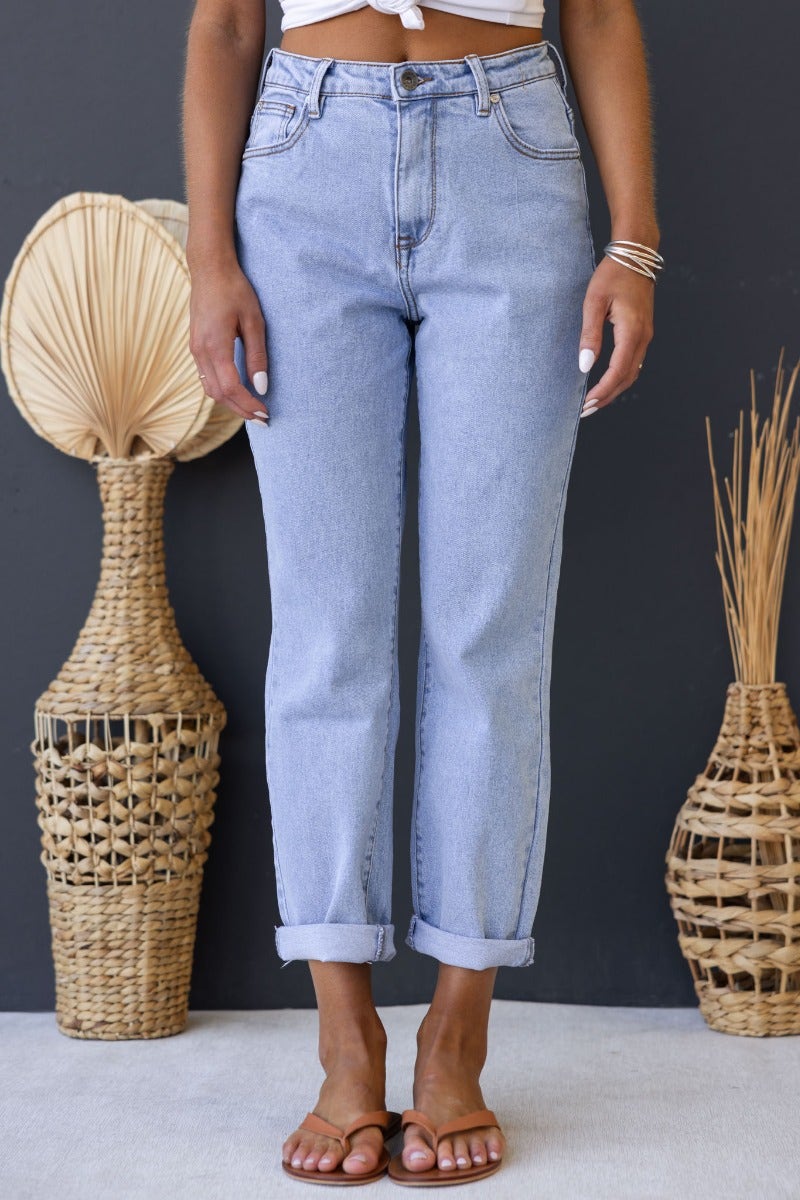 Model wearing Dori mom jeans in light wash, featuring mid-high waist and rolled cuffs, paired with a casual top.
