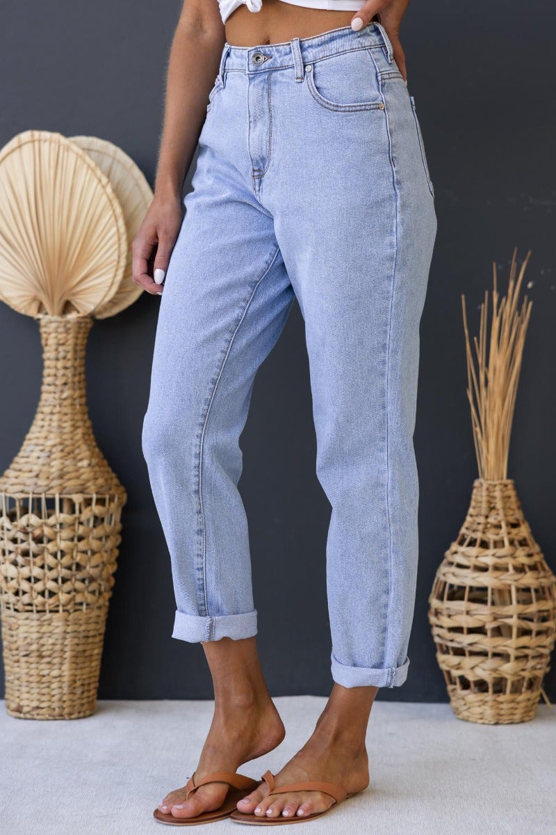 Dori mom jeans in light denim with mid-high waist and rolled cuffs, paired with casual sandals.