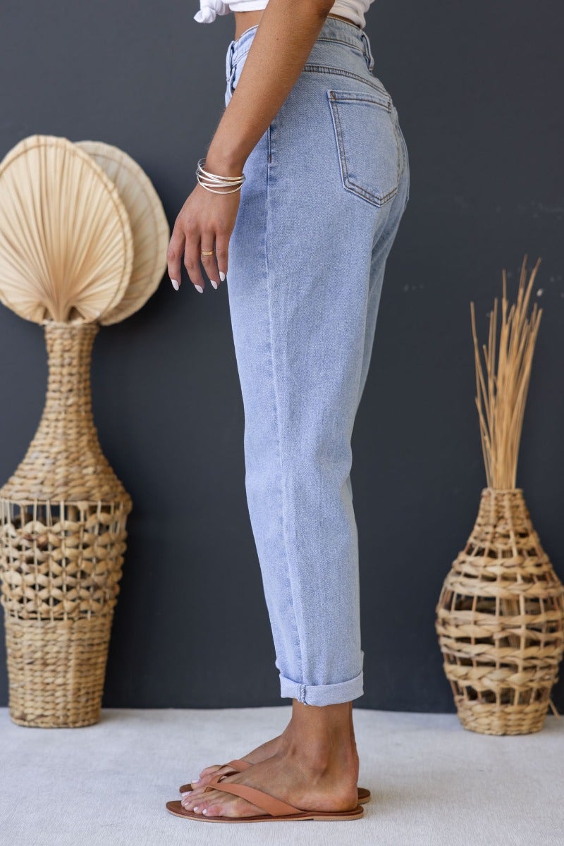 Side view of a person wearing light blue Dori mom jeans with a mid-high waist fit, paired with sandals.