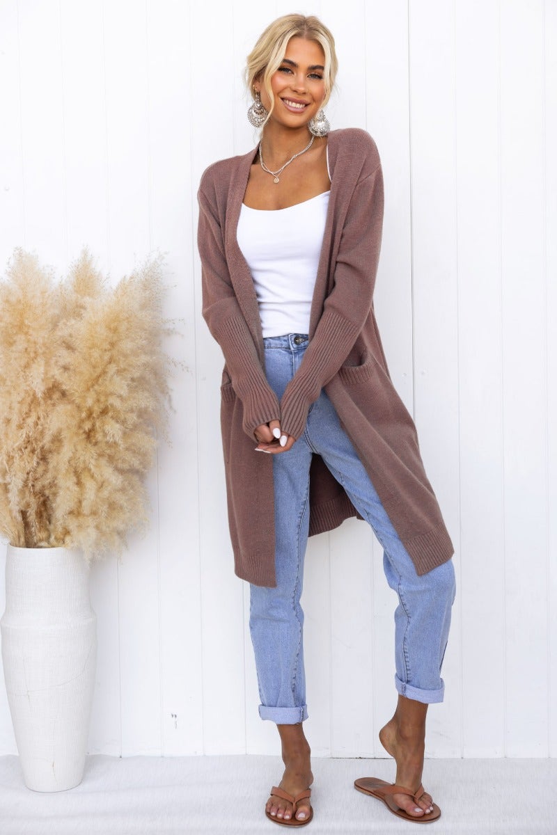 Model wearing a longline ribbed Motherly Cardigan in brown with front pockets, styled with a white tank and jeans.