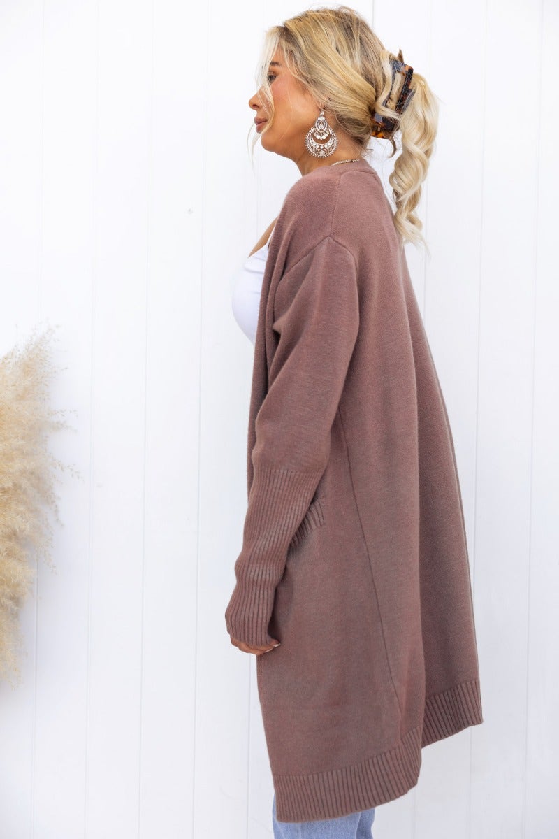 Stylish motherly cardigan in ribbed knit, featuring a longline fit and pockets, modeled with relaxed elegance.