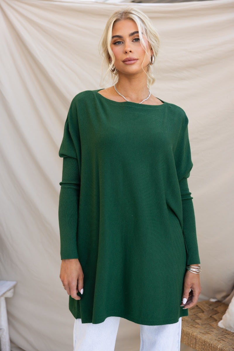 Model wearing a cosy oversized green knit top dress with full-length sleeves and relaxed fit.
