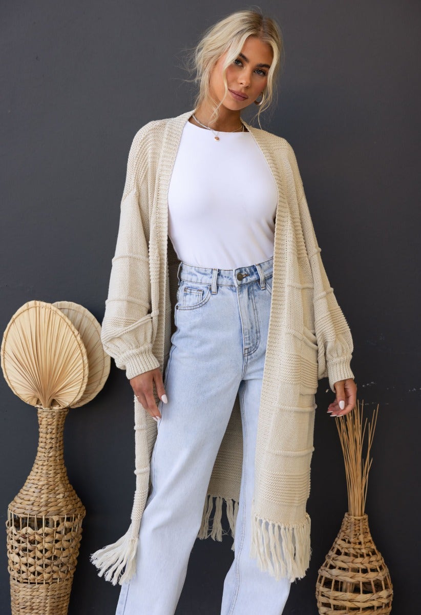 Zeddie Cardigan in beige worn over a white top, styled with light jeans, featuring fringed edges and relaxed fit.